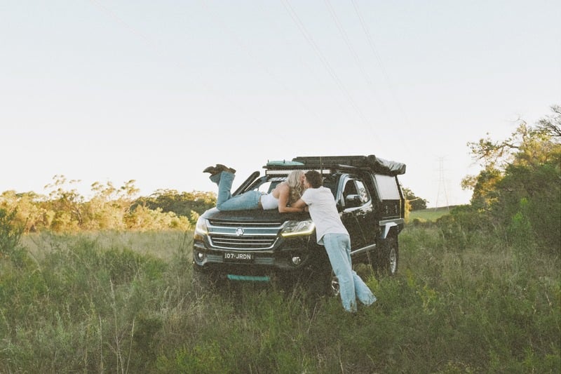 Couple standing beside a four wheel drive in a green paddock